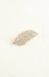 Decorative feather brooch with gemstones on a light background