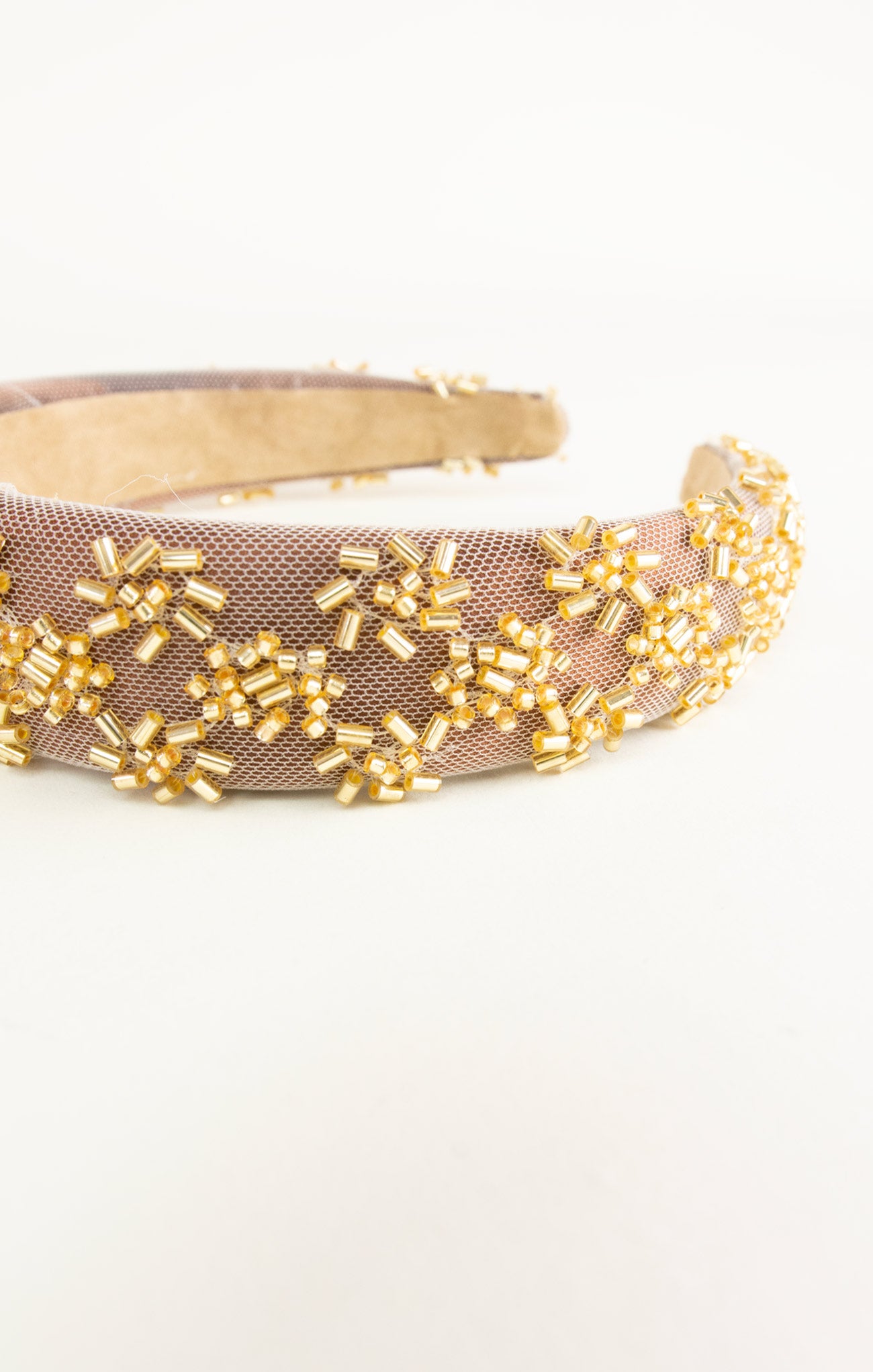 Beige headband with gold bead embellishments on a white background