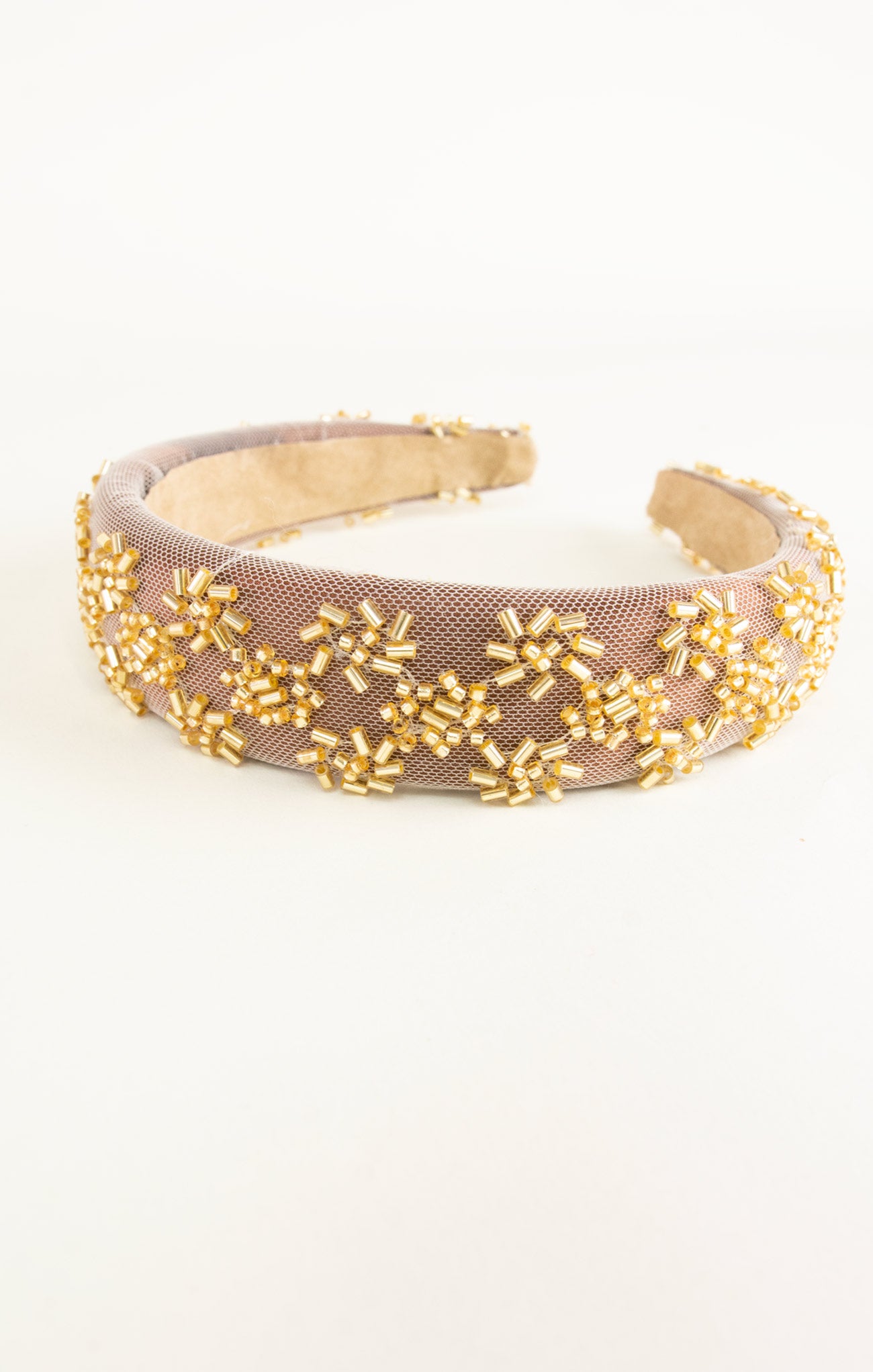 Beaded headband with gold beads on a beige background