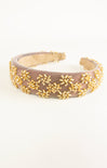 Beaded headband with gold beads on a beige background