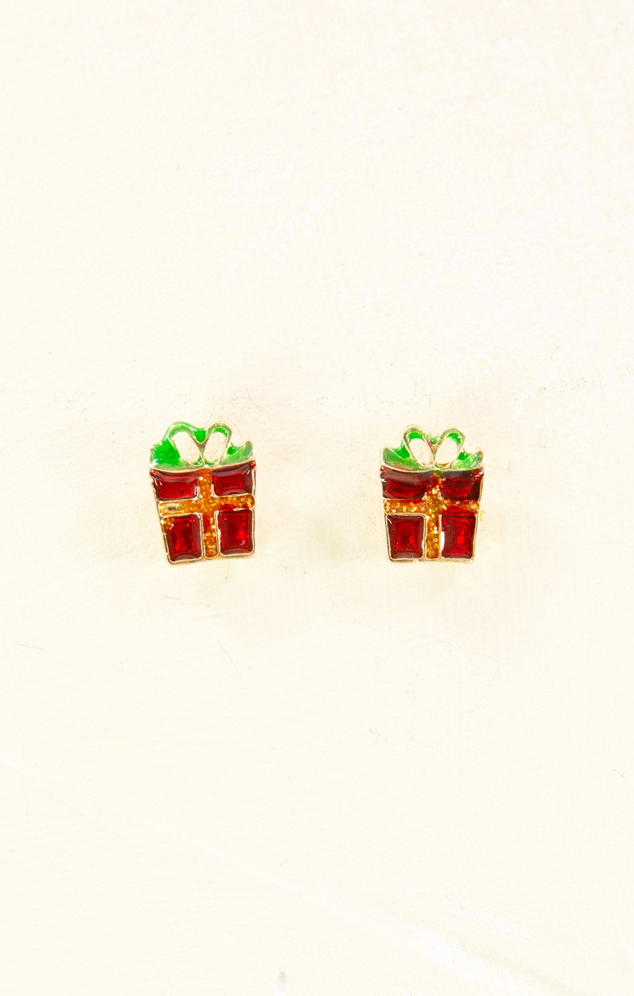 Pair of earrings shaped like gift boxes with green bows on a white background