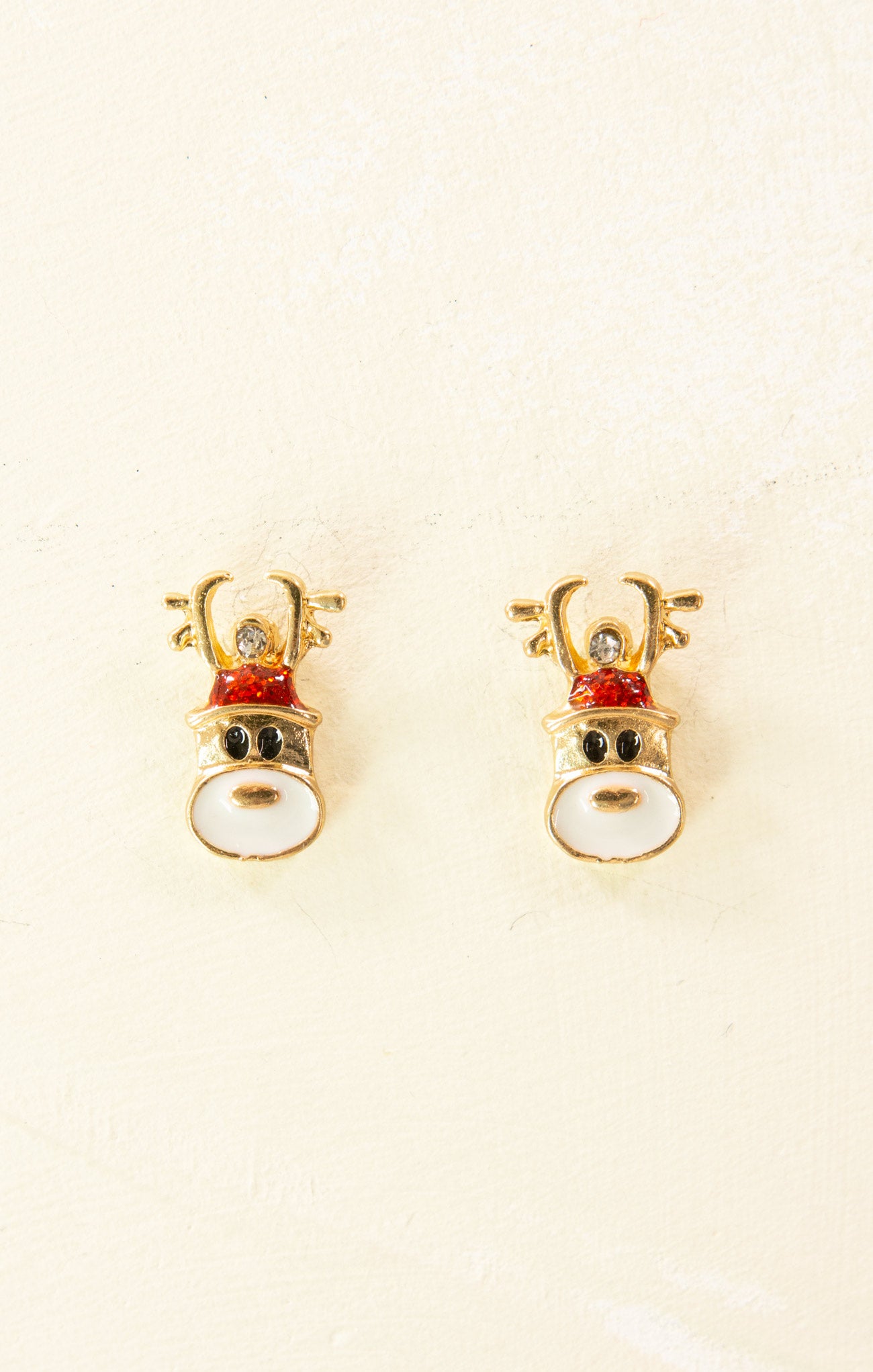 Pair of gold reindeer-shaped earrings on a beige background