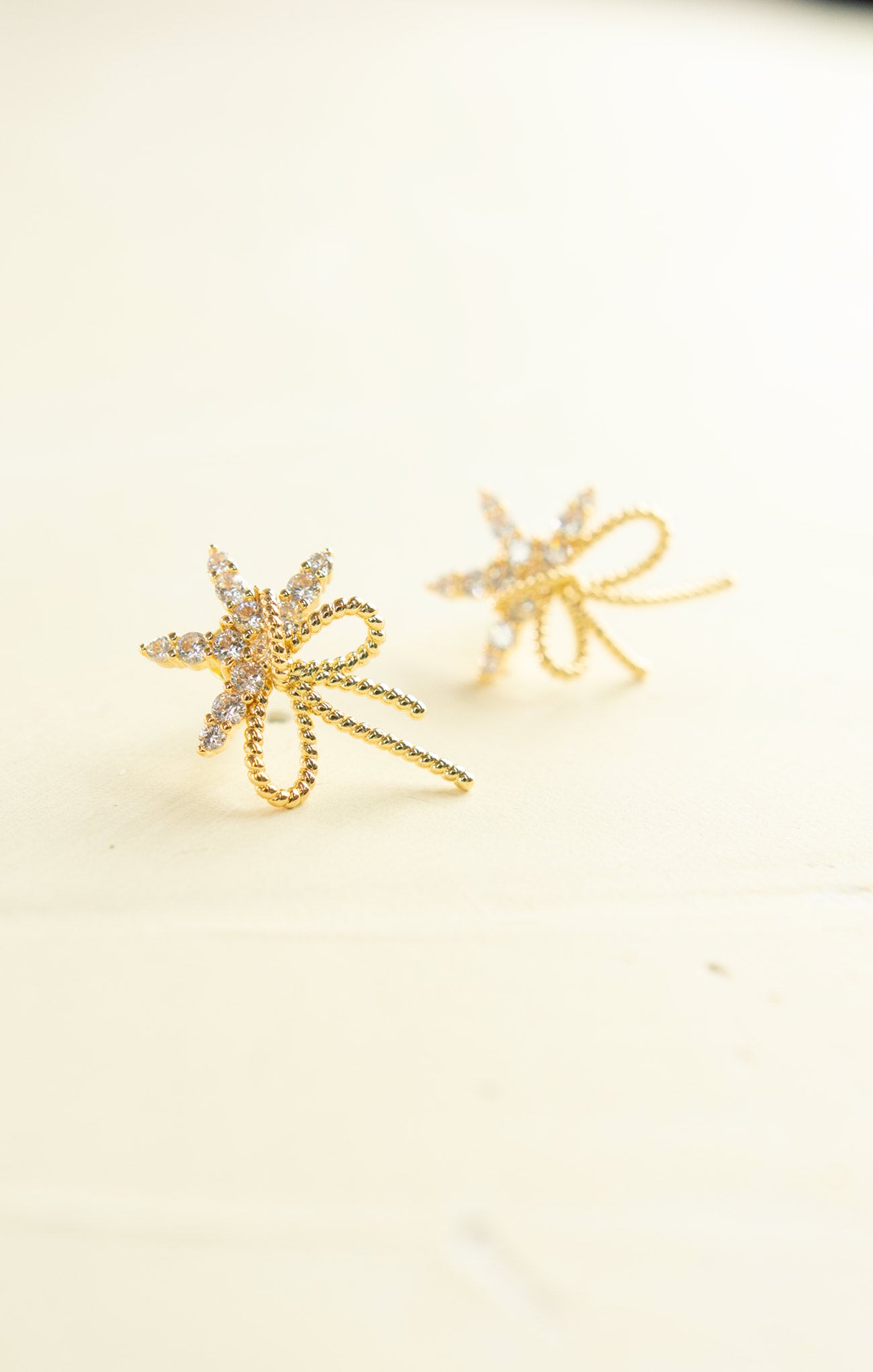 Gold star-shaped earrings on a light beige background