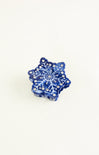 Blue snowflake-shaped object with rhinestones on a white background