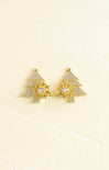 Gold tree-shaped earrings with clear stones on a beige background
