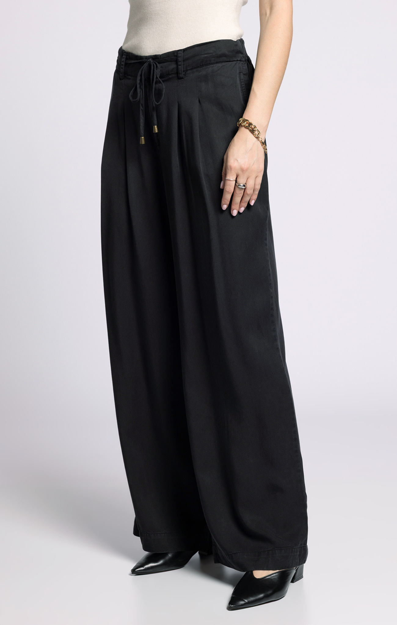 Person wearing black wide-leg pants on a white background