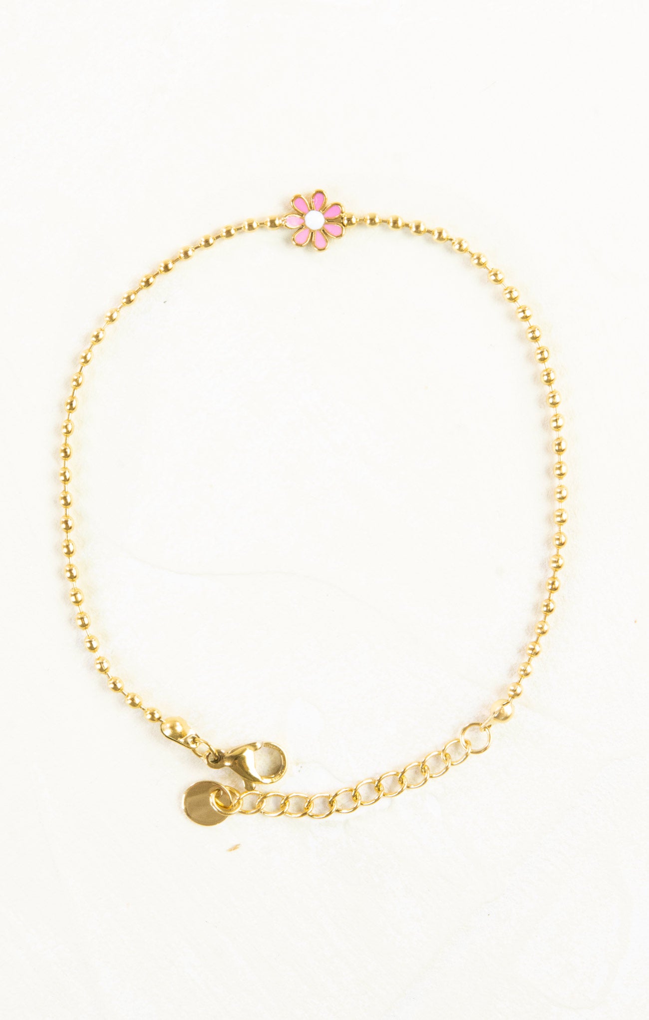 Gold bracelet with a pink flower charm on a white background