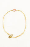 Gold bracelet with a pink flower charm on a white background