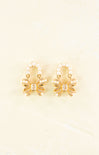 Pair of gold earrings with pearl accents on a beige background