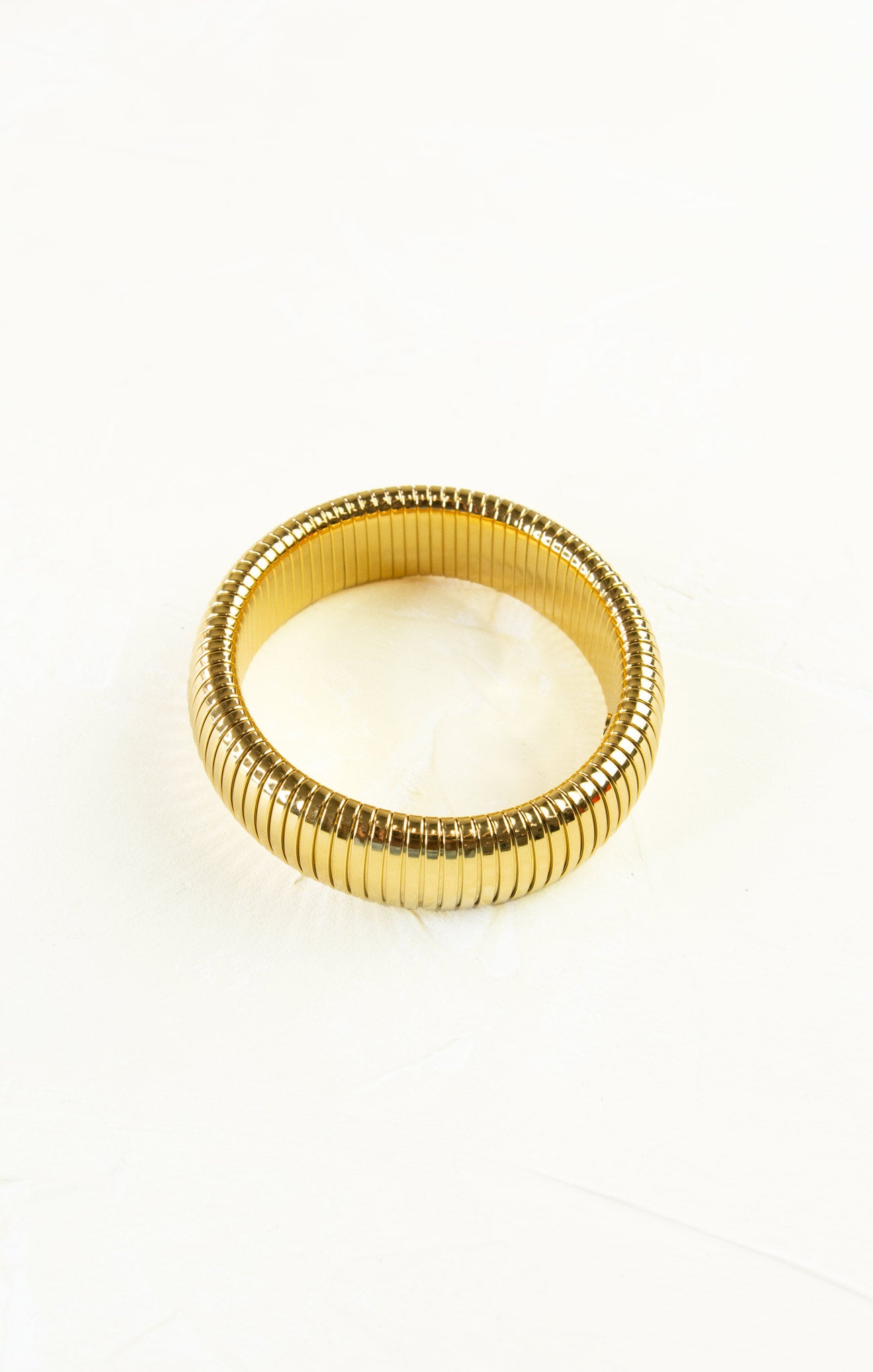 Gold ring with a ribbed design on a white background