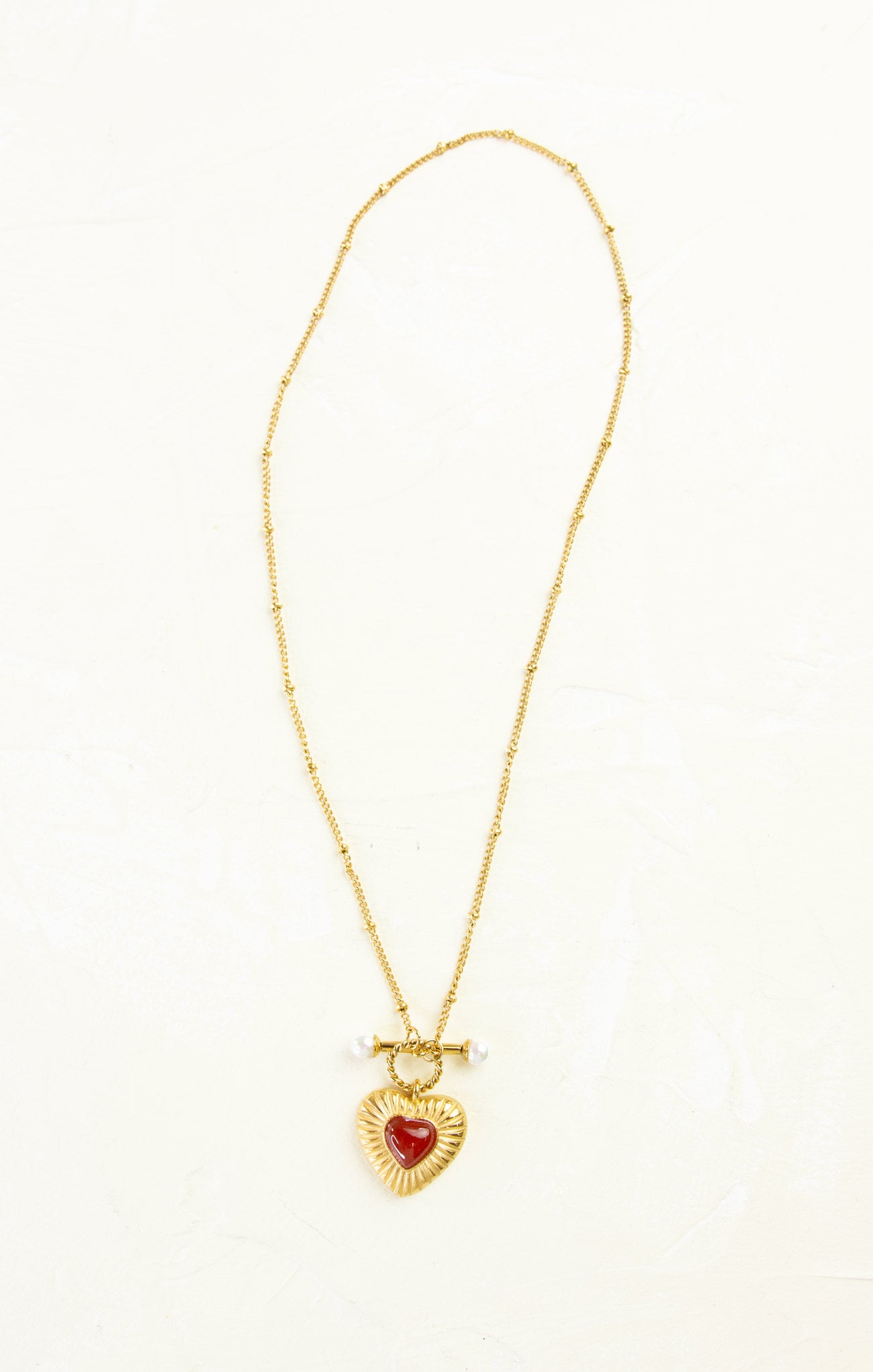 Gold necklace with a heart-shaped pendant on a white background