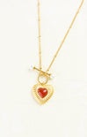 Gold necklace with a heart-shaped red pendant on a white background