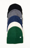 Stack of five knit beanie hats in black, gray, blue, white, and green on a white background.