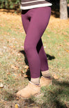 Person wearing purple leggings and beige boots on a grassy ground.