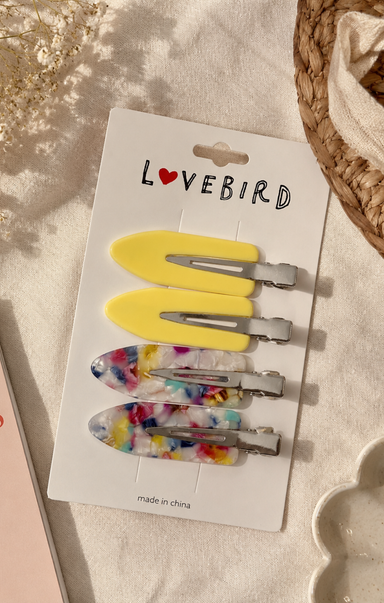 Set of hair clips on a 'Lovebird' branded card with a wicker basket in the background.