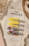 Set of hair clips on a 'Lovebird' branded card with a wicker basket in the background.