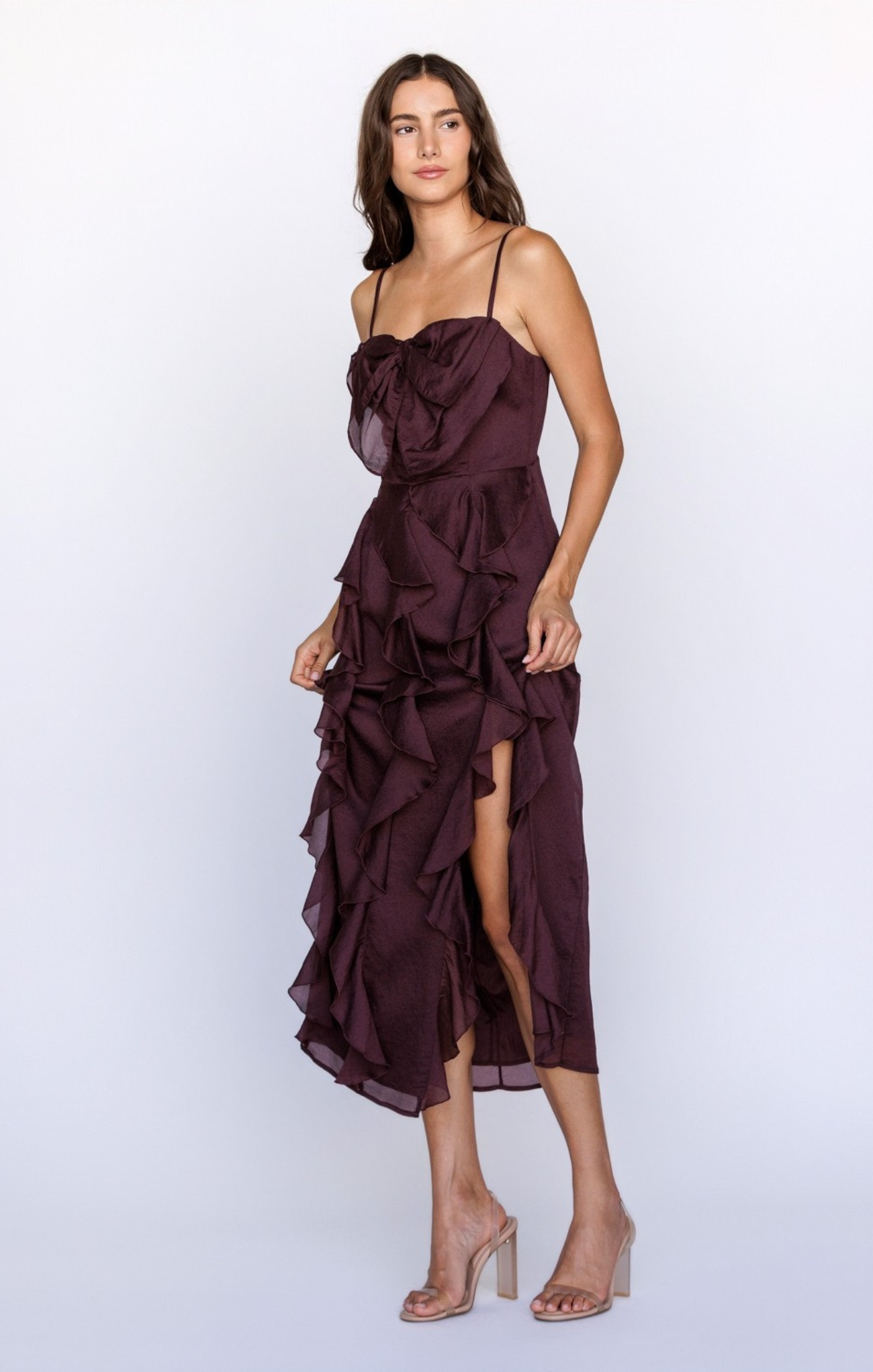 Woman wearing a dark purple dress with ruffled layers on a white background