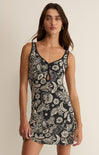 Woman wearing a black floral dress against a beige background