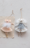 Two decorative mouse figurines in dresses hanging on a textured wall.