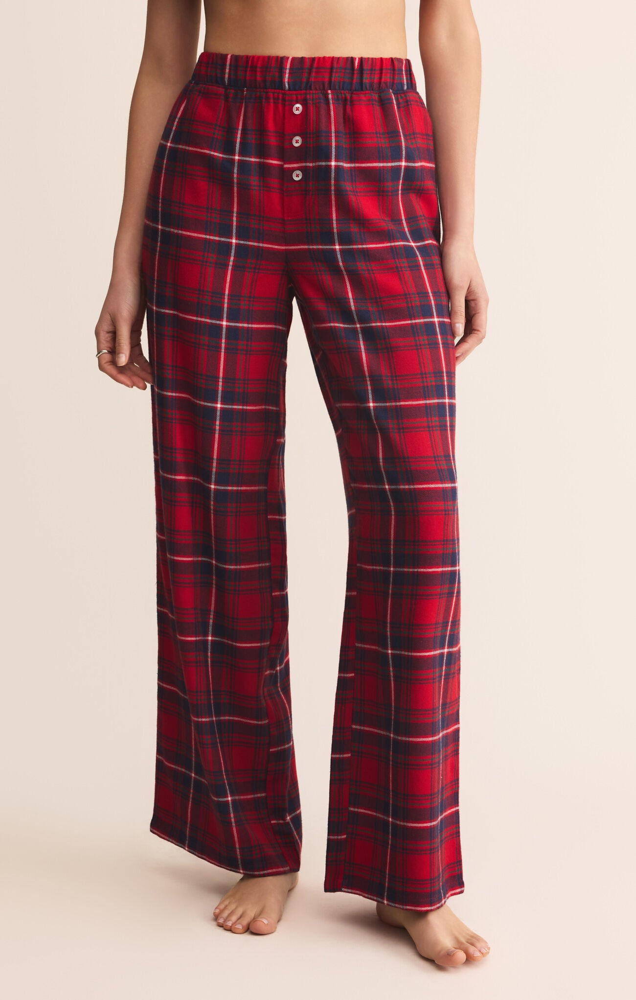 Red plaid pajama pants worn by a person on a beige background