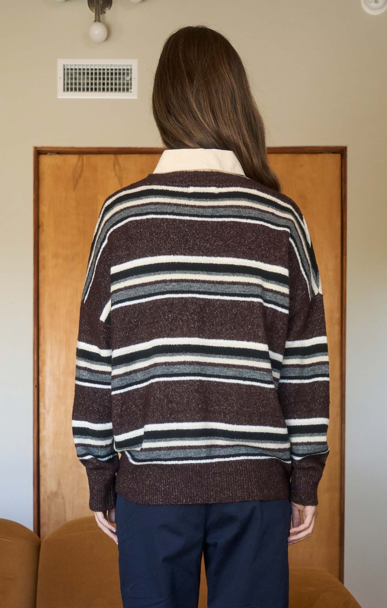 Person wearing a striped sweater with a neutral background