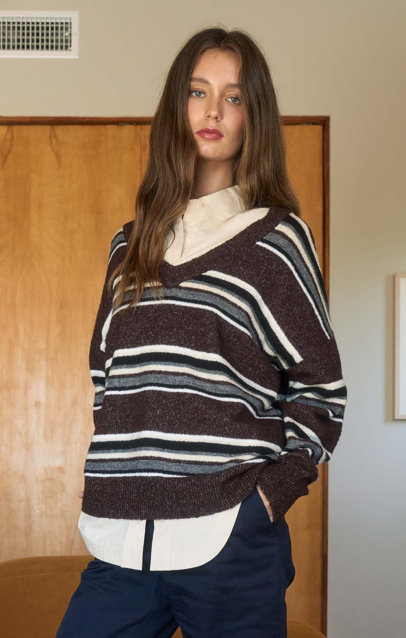Woman wearing a striped sweater over a white shirt in an indoor setting