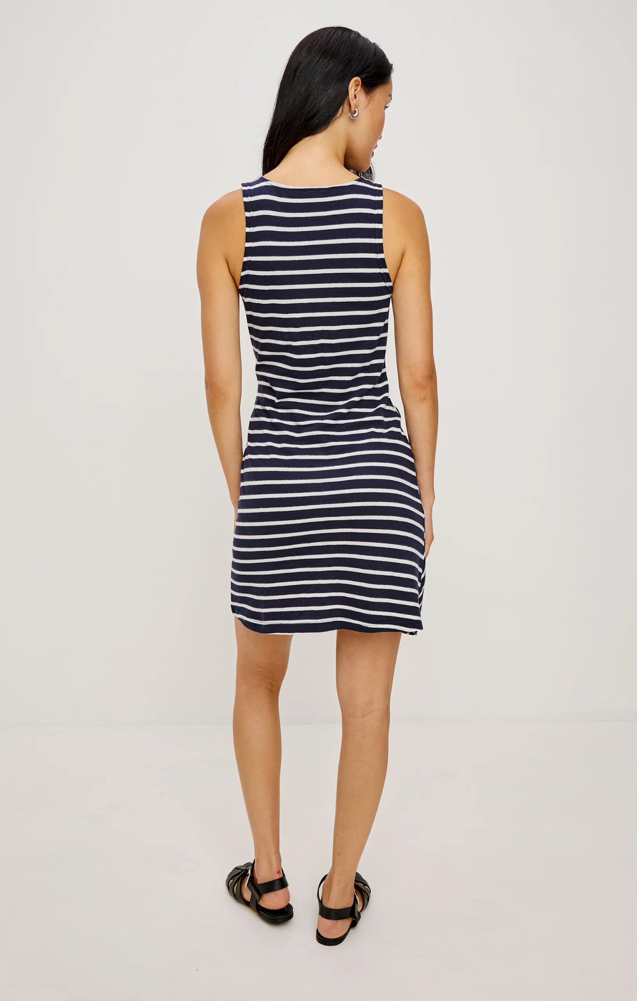 Woman wearing a navy and white striped dress on a plain background