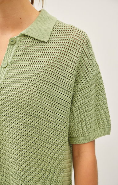 Green knitted polo shirt on a plain background