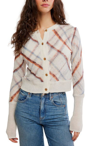 A woman wearing a cream-colored knit cardigan with a rust-orange and light blue plaid pattern, paired with blue jeans, shown against a plain white background.