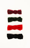 Four velvet hair bows in red, green, black, and red on a white background