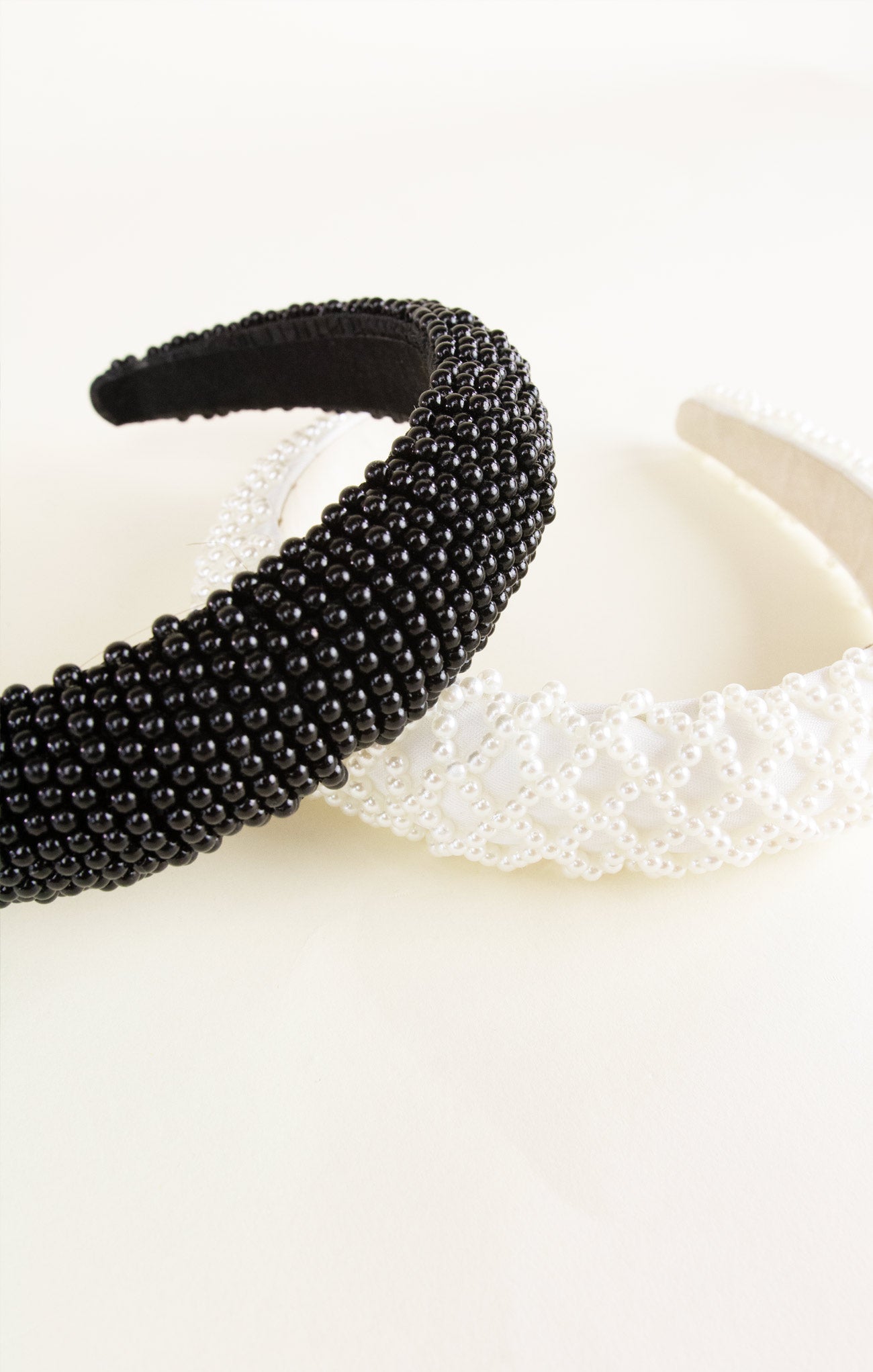 Black beaded headband and white lace headband on a light background