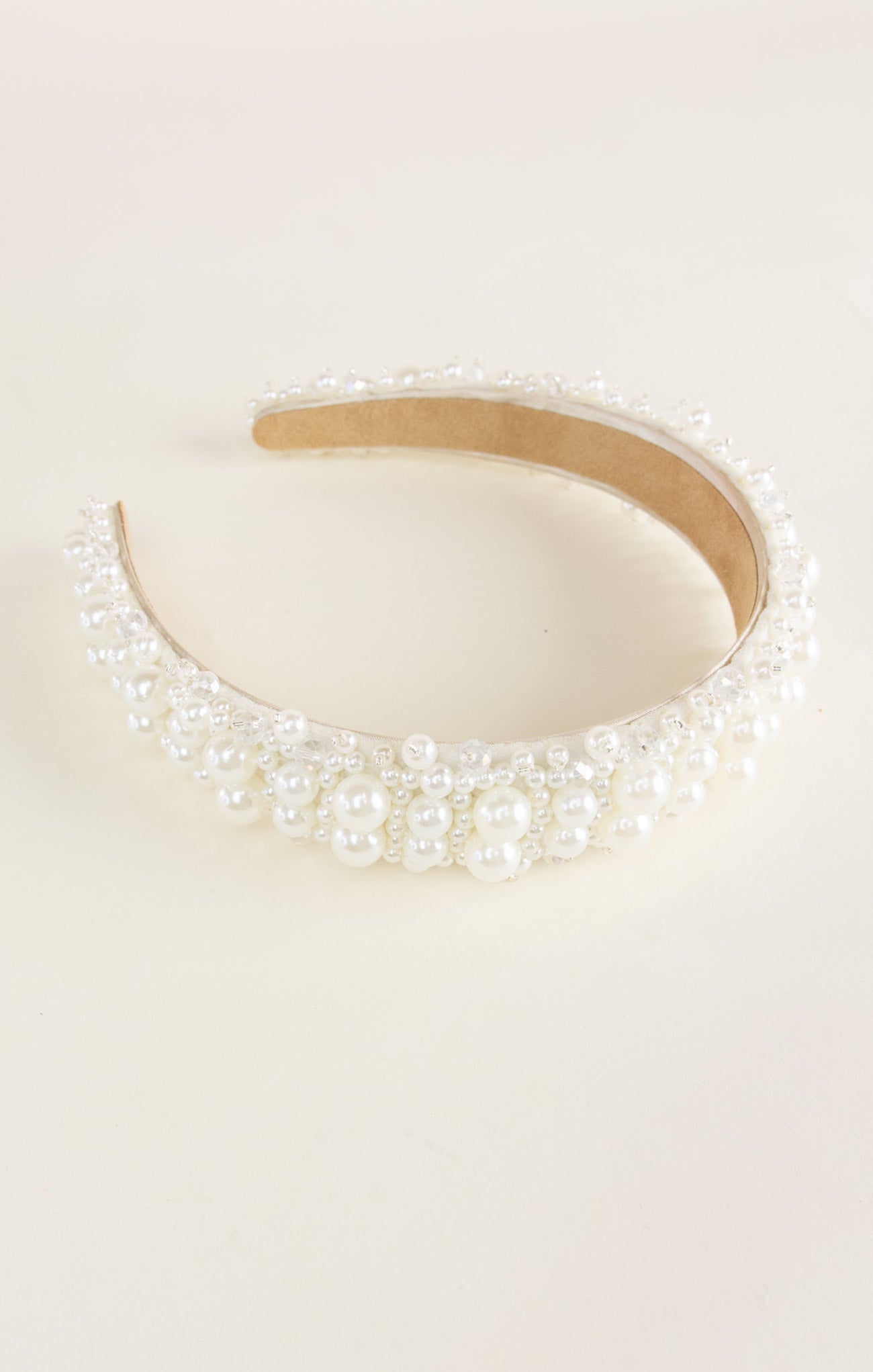 Pearl-encrusted headband on a light beige background