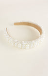 Pearl-encrusted headband on a light beige background
