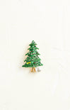 Green Christmas tree-shaped brooch with a pearl on a white background