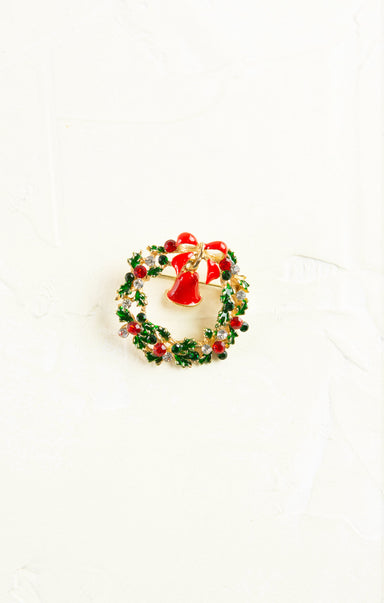 Christmas-themed brooch with a wreath and Santa Claus figure on a white background