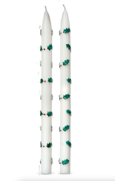 Two white candles with green and red designs on a white background