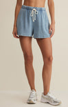 Person wearing light blue shorts with a beige background