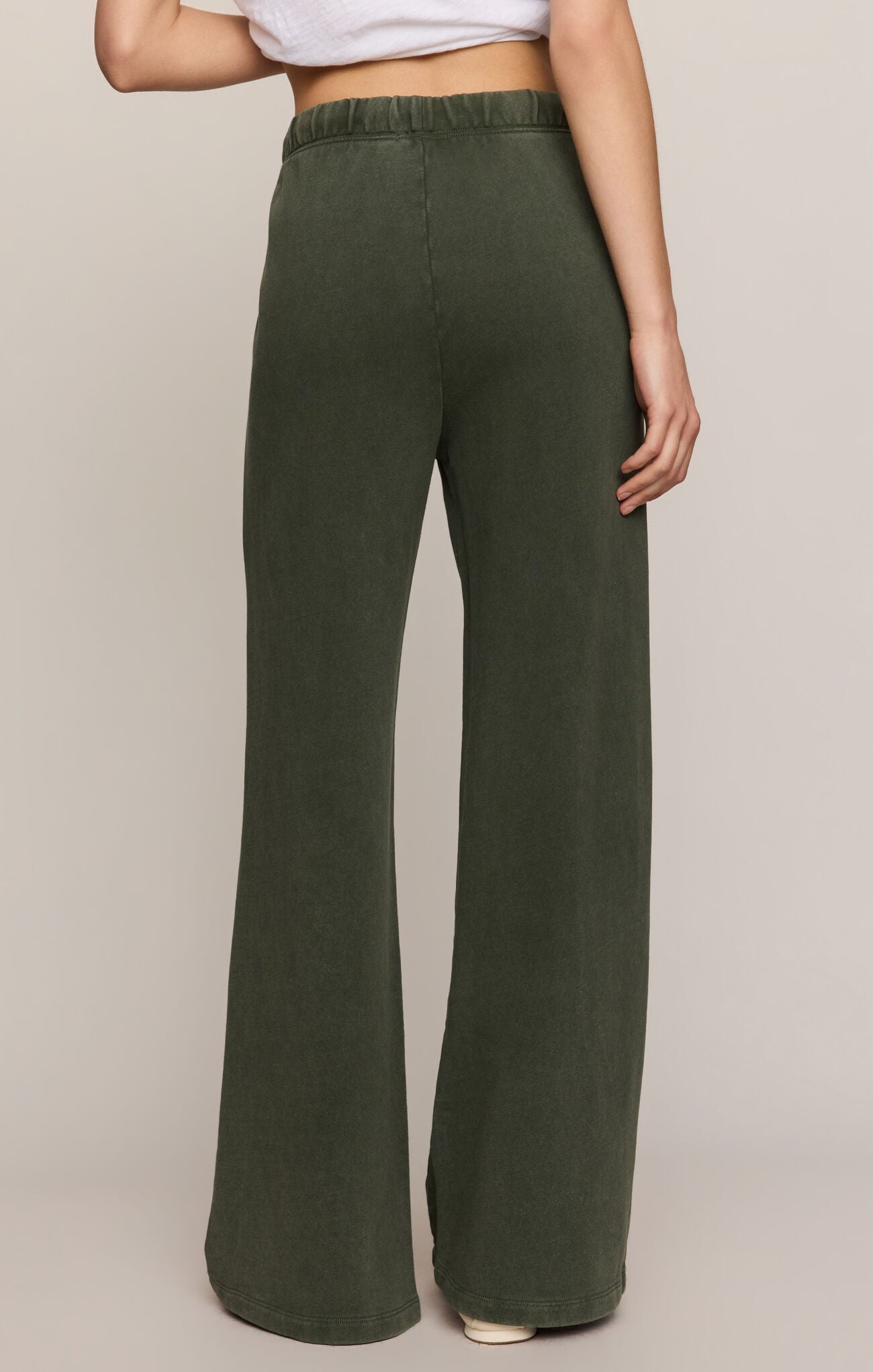 Person wearing green wide-leg pants on a beige background