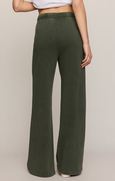 Person wearing green wide-leg pants on a beige background