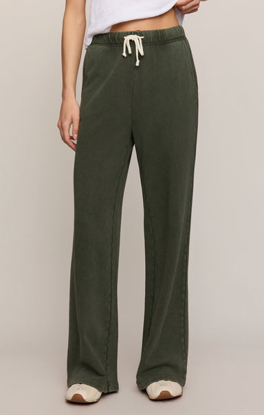 Person wearing green pants with a drawstring on a plain background