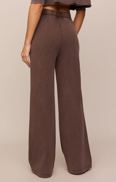 Brown wide-leg pants worn by a person on a beige background