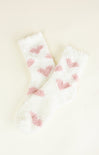Pair of white socks with pink heart patterns on a light beige background