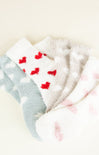 Three pairs of socks with red heart patterns on a light background