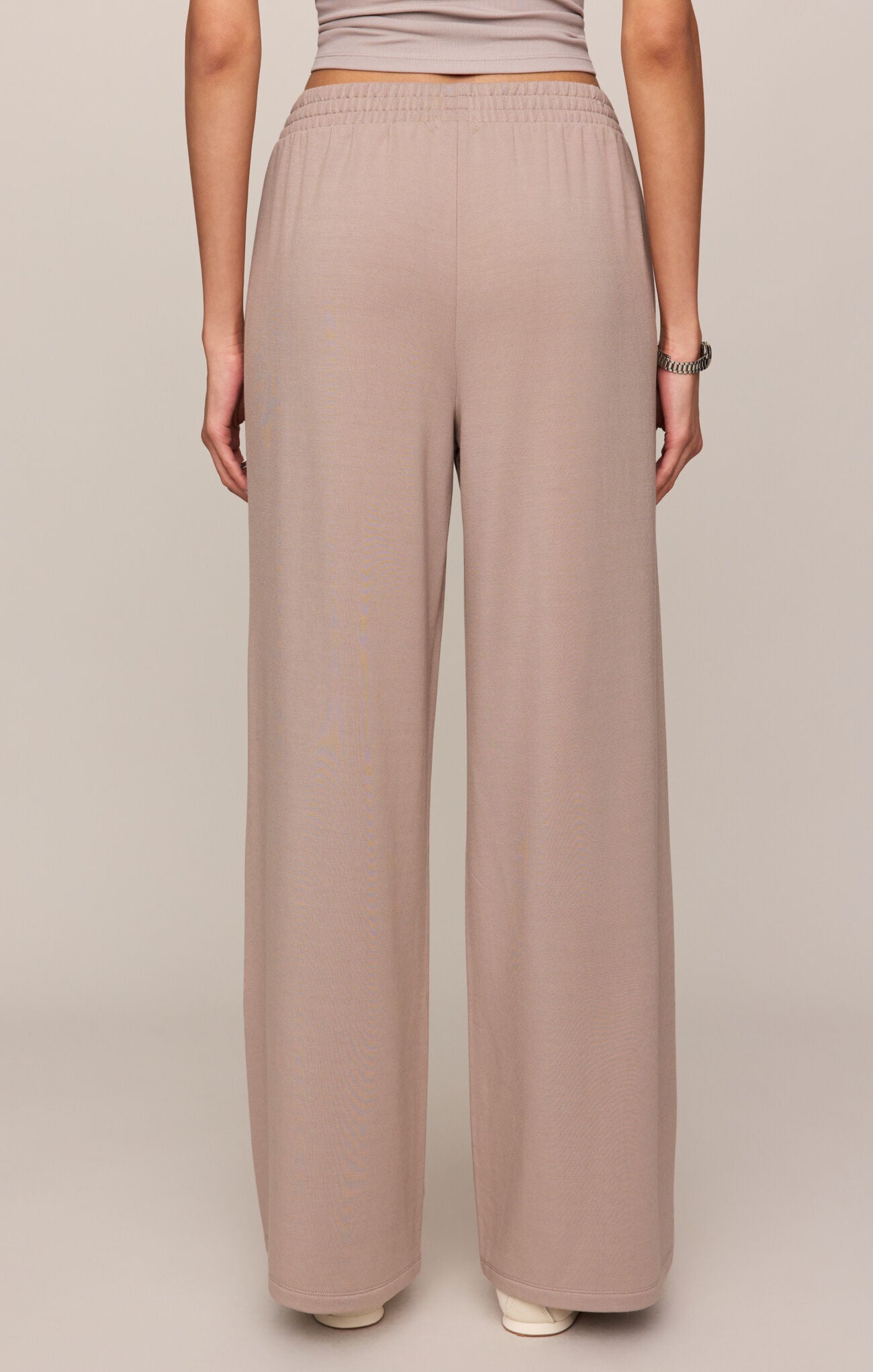 Person wearing beige wide-leg pants on a plain background