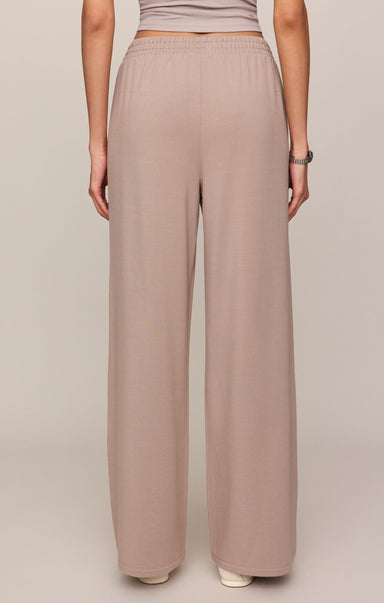 Person wearing beige wide-leg pants on a plain background