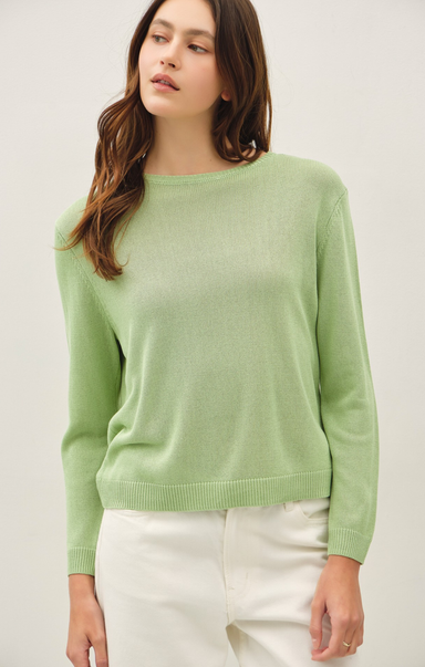 Woman wearing a light green sweater against a plain background