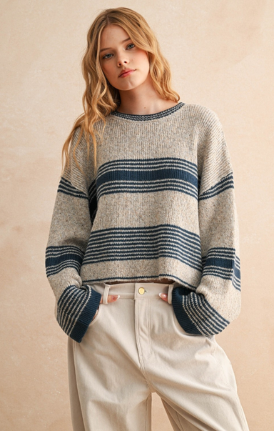 Woman wearing a striped sweater and light pants against a beige background