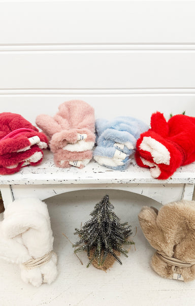 Colorful plush mittens on a white surface with a small decorative tree.