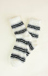 Pair of white fuzzy socks with black stripes on a light beige background