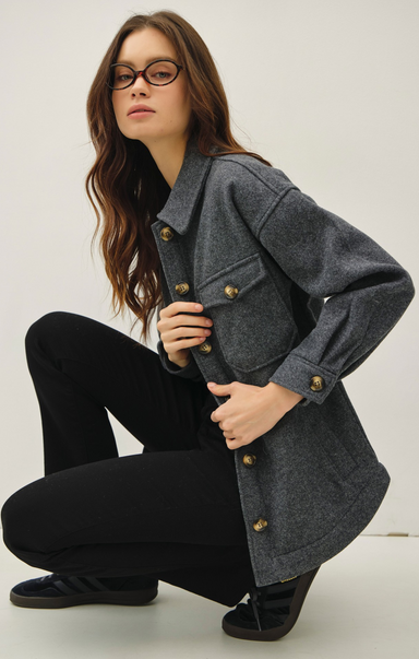 Woman wearing a gray coat with gold buttons on a white background